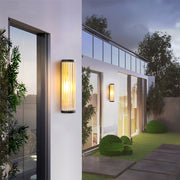 Tall cylindrical outdoor wall LED light with ribbed or fluted glass, mounted on a white exterior wall of a modern villa.