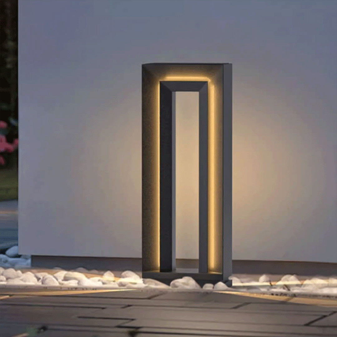 Tall modern lighted bollards LED fixture installed near exterior wall casting soft vertical illumination.
