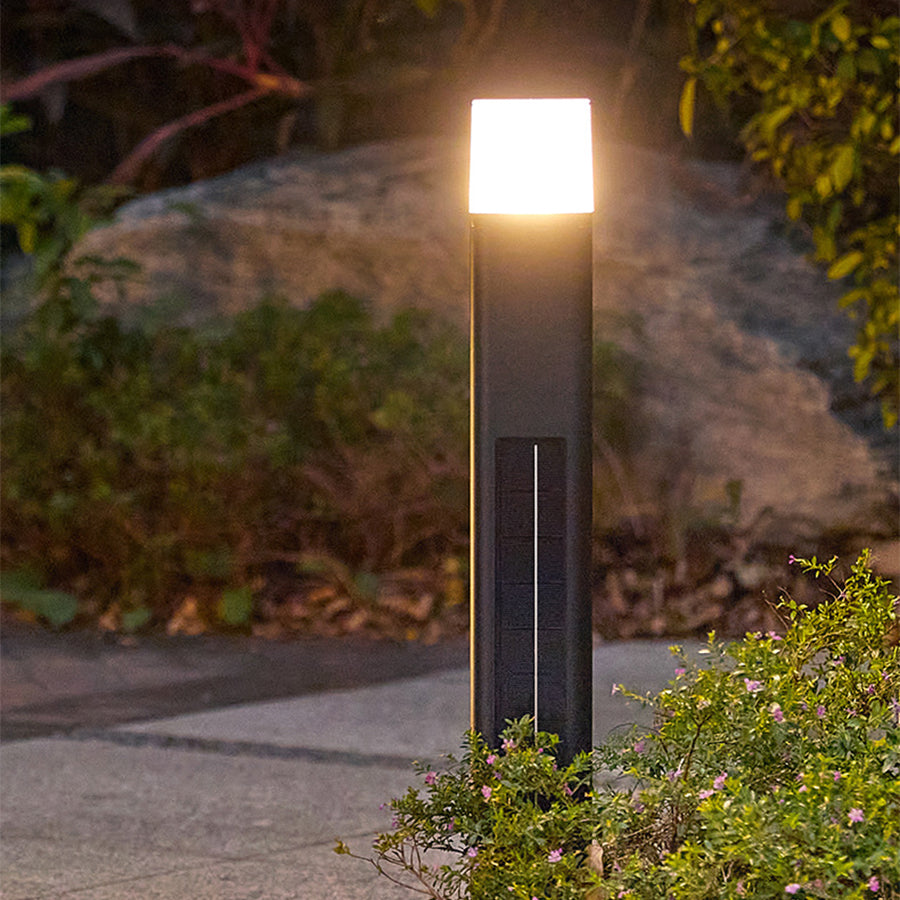 Tall solar pathway light with clean geometric design positioned along stone garden border