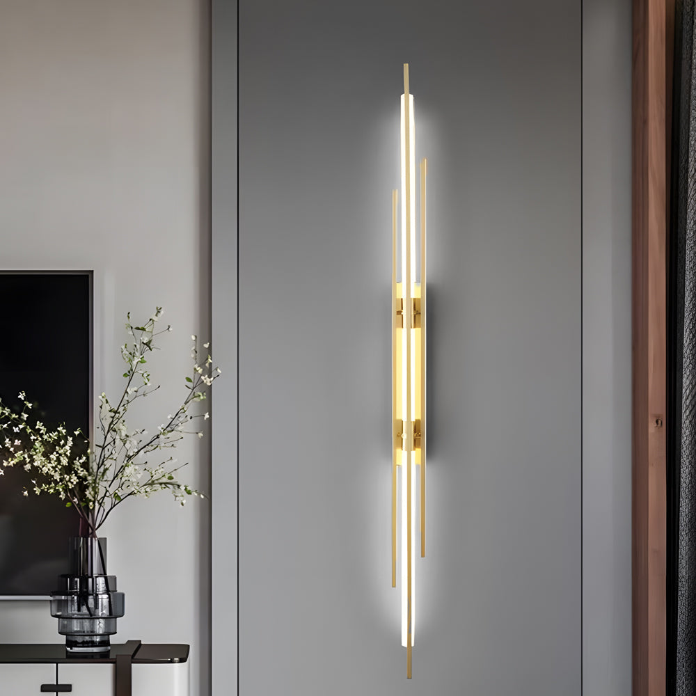 Tall vertical tube wall sconce installed beside console table with decor.