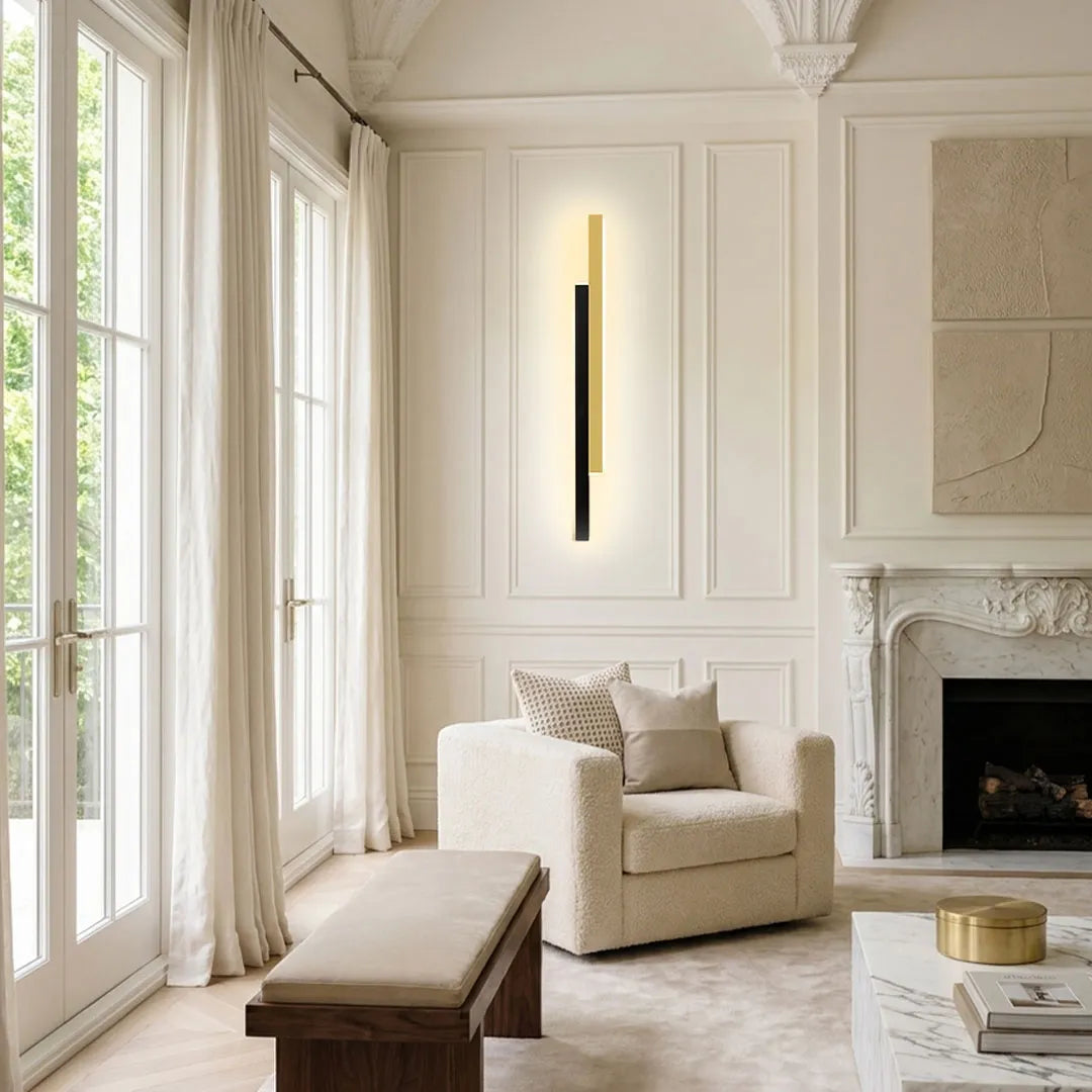 Tall vertical wall light mounted in a classic living room with fireplace, armchair, and French windows.