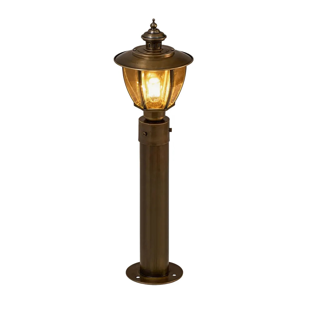 Tall vintage brass bollard light with classic lantern head and warm lighting
