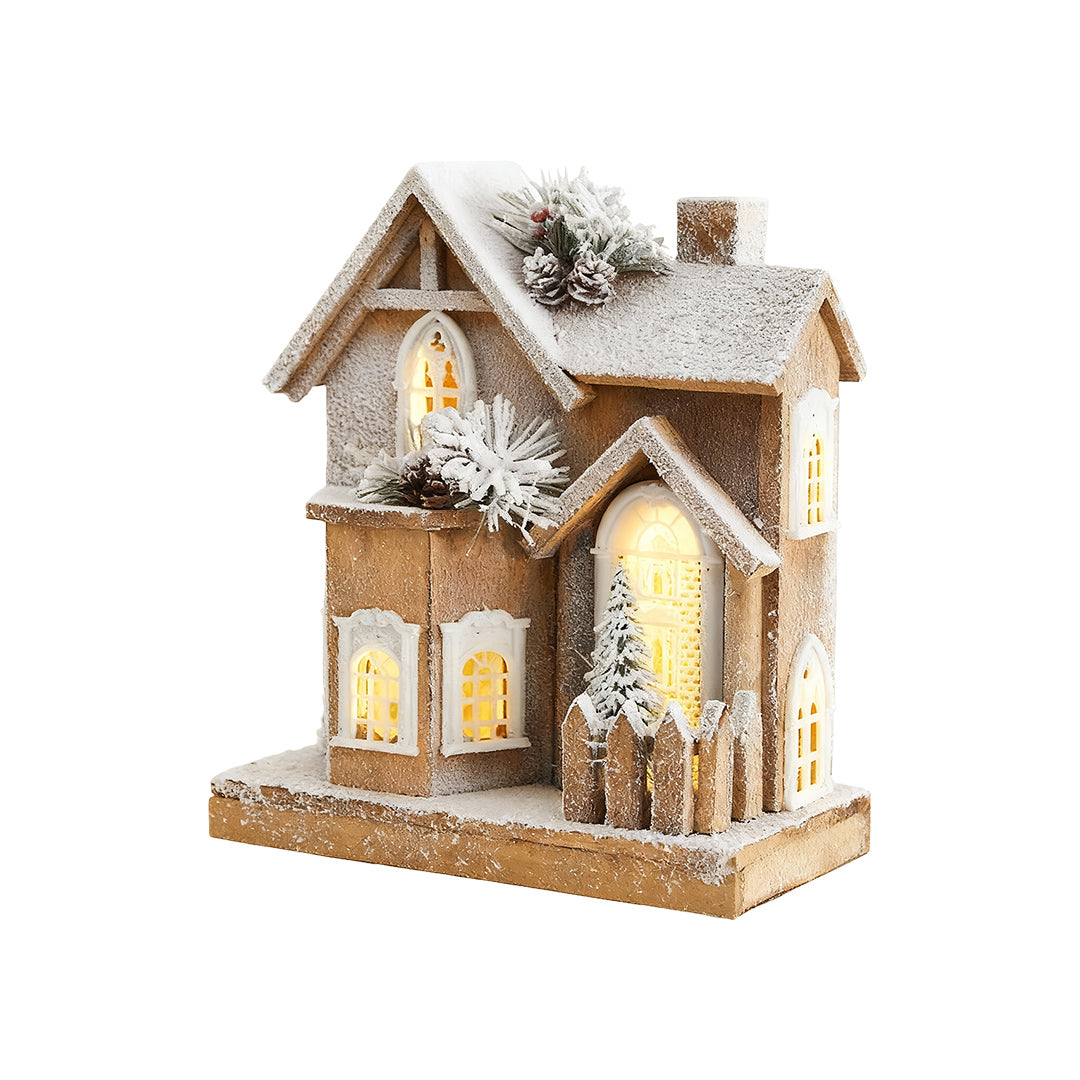 Tall wooden Christmas cottage with frosted roof, pine decor, and warm LED lighting.