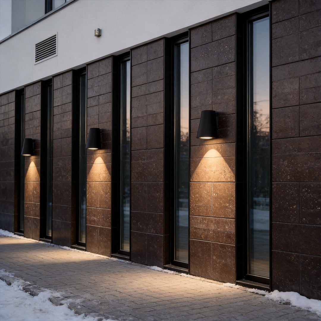 Tapered wall light providing modern illumination along a building facade.