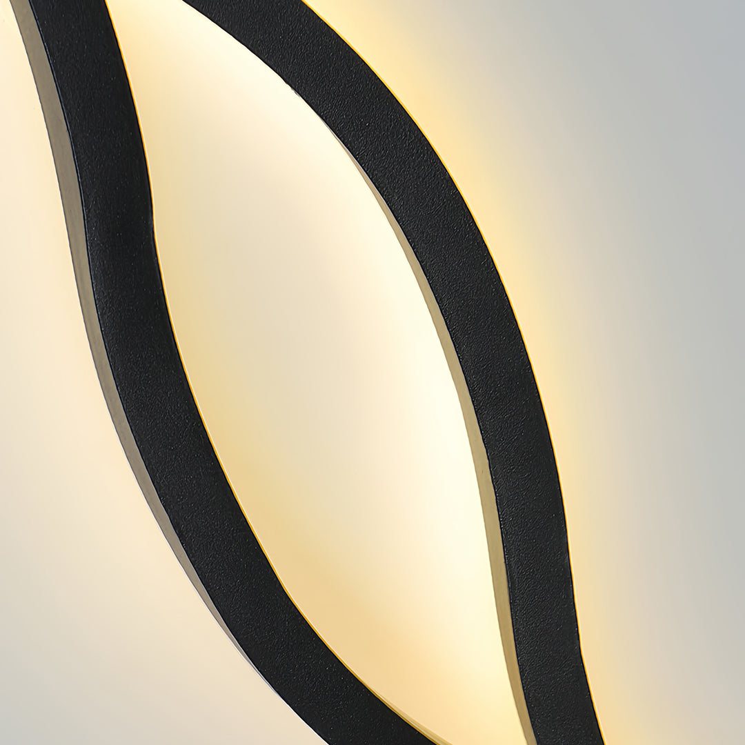Close-up of the integrated LED glow and textured black finish on the artistic wave bedside wall light.