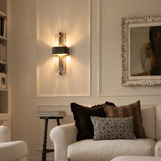 Textured glass wall sconce mounted above a sofa in a cozy living room with warm ambient lighting.