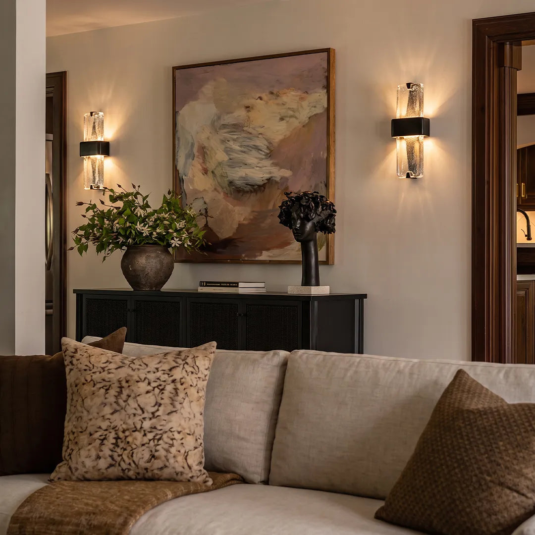 Textured glass wall sconces installed above a console table in a warm neutral living room.