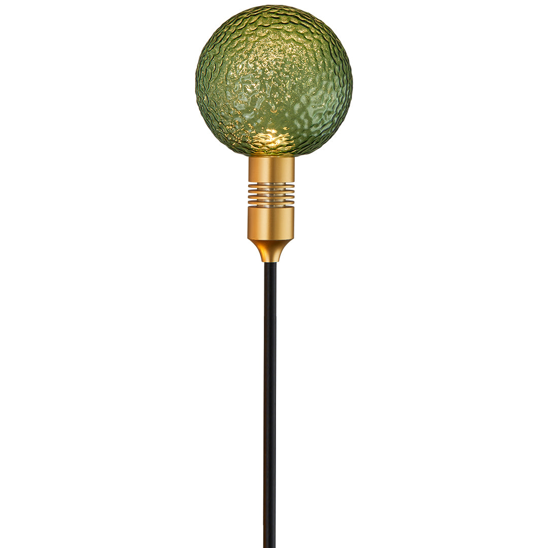 Textured green garden globe stake light enhancing greenery with warm path landscape lighting.