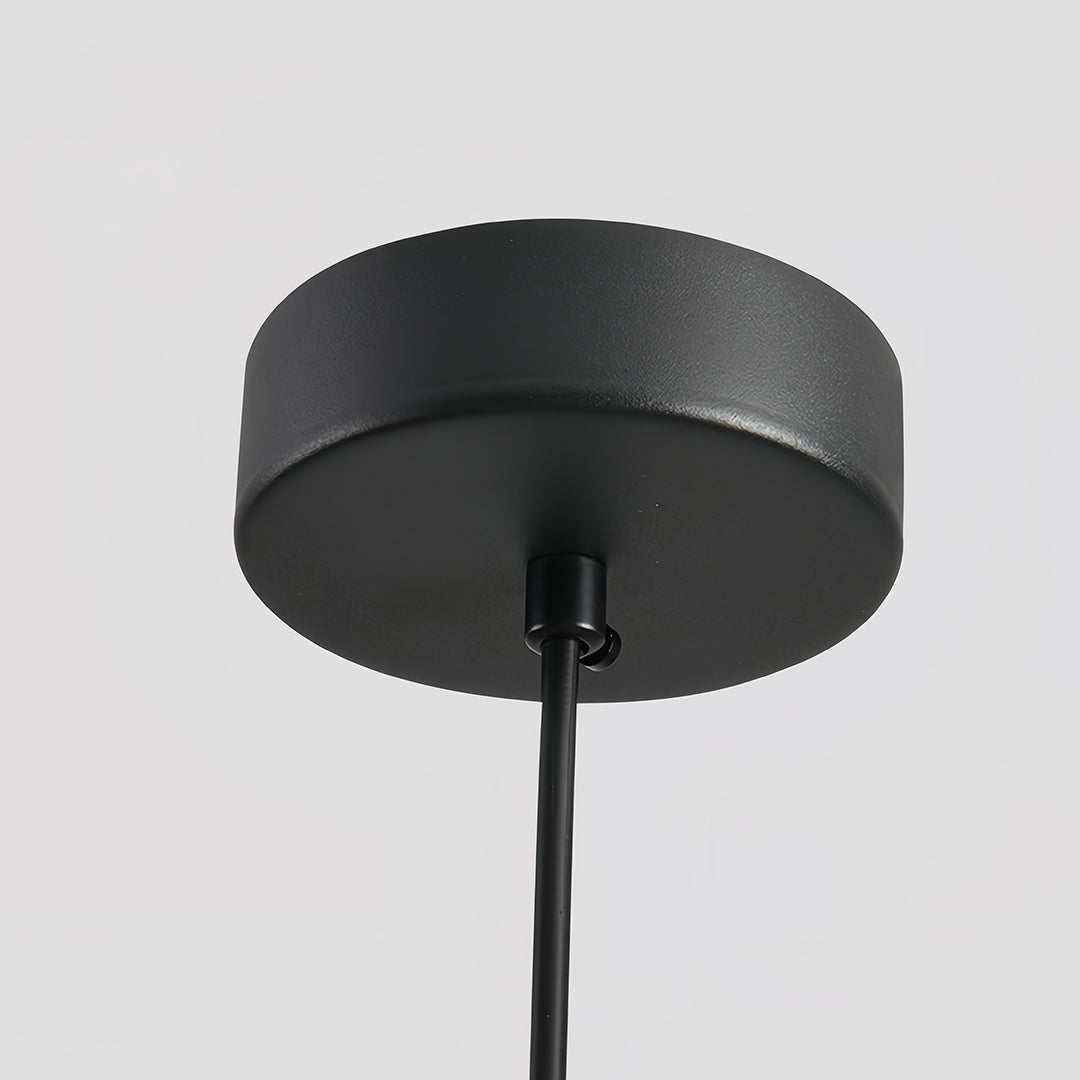 Close-up of the textured matte black ceiling canopy and cord for an adjustable pendant light installation.