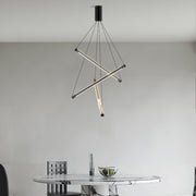 Minimalist LED linear chandelier with three intersecting gold bars and hanging thin cables in a modern dining room.