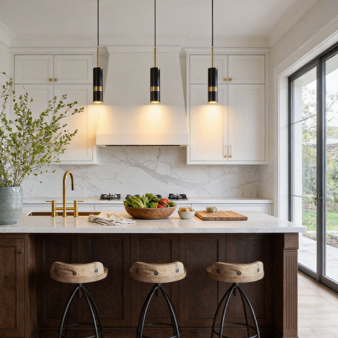 Three black adjustable cylindrical pendant lights over a marble kitchen island and stools.