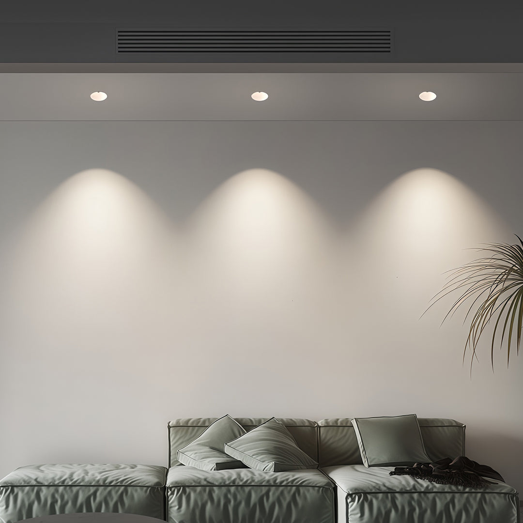 Three flush mount spotlights creating even wall washing in modern grey bedroom with textured artwork