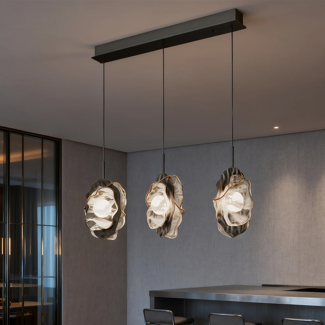 Three fun pendant lights arranged linearly over kitchen island in sleek black and grey interior