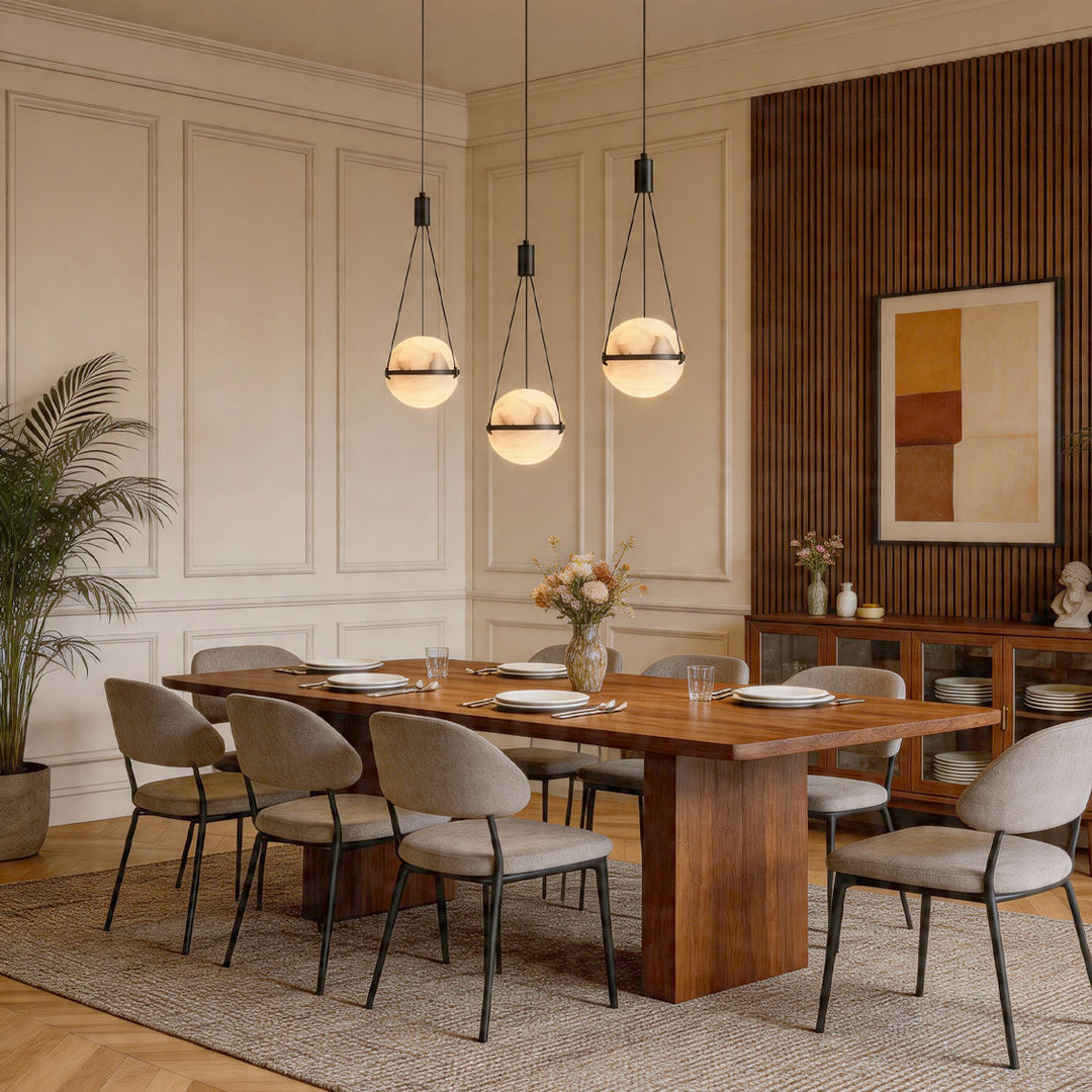 Three globe pendant light fixtures illuminating a large wood dining table with elegant chairs.