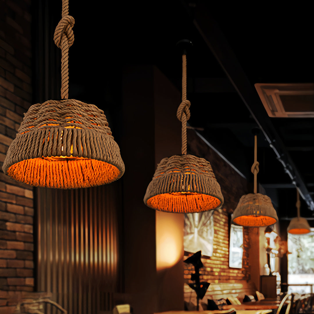 Three glowing rope pendant lights hanging over tables against a dark exposed brick wall in a cozy bar or cafe.