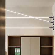Three modern led lights strips for room glowing brightly across a wall above a wooden cabinet.