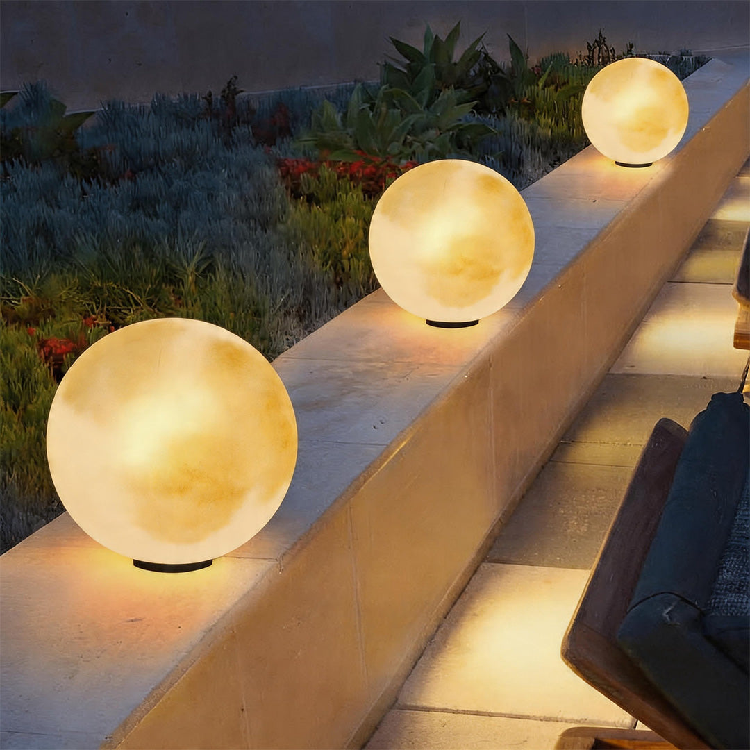 Three moon pillar lights illuminating a terraced stone wall in a luxury outdoor garden space.