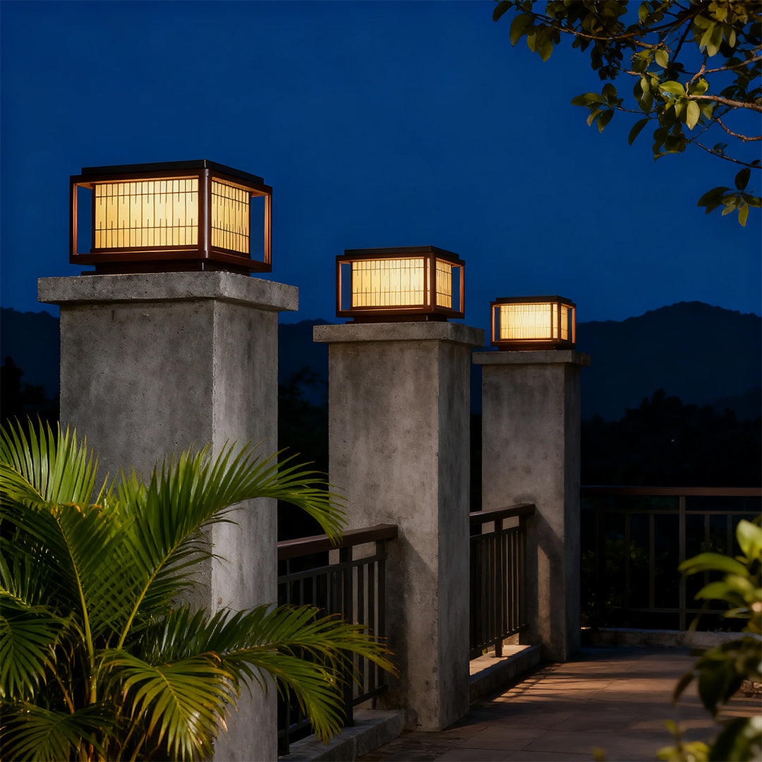 Three outdoor pillar LED lights arranged on concrete pillars creating entrance lighting with mountain backdrop.