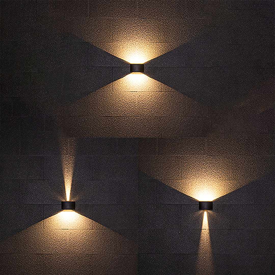 Three outdoor up down wall lights creating layered illumination on dark facade