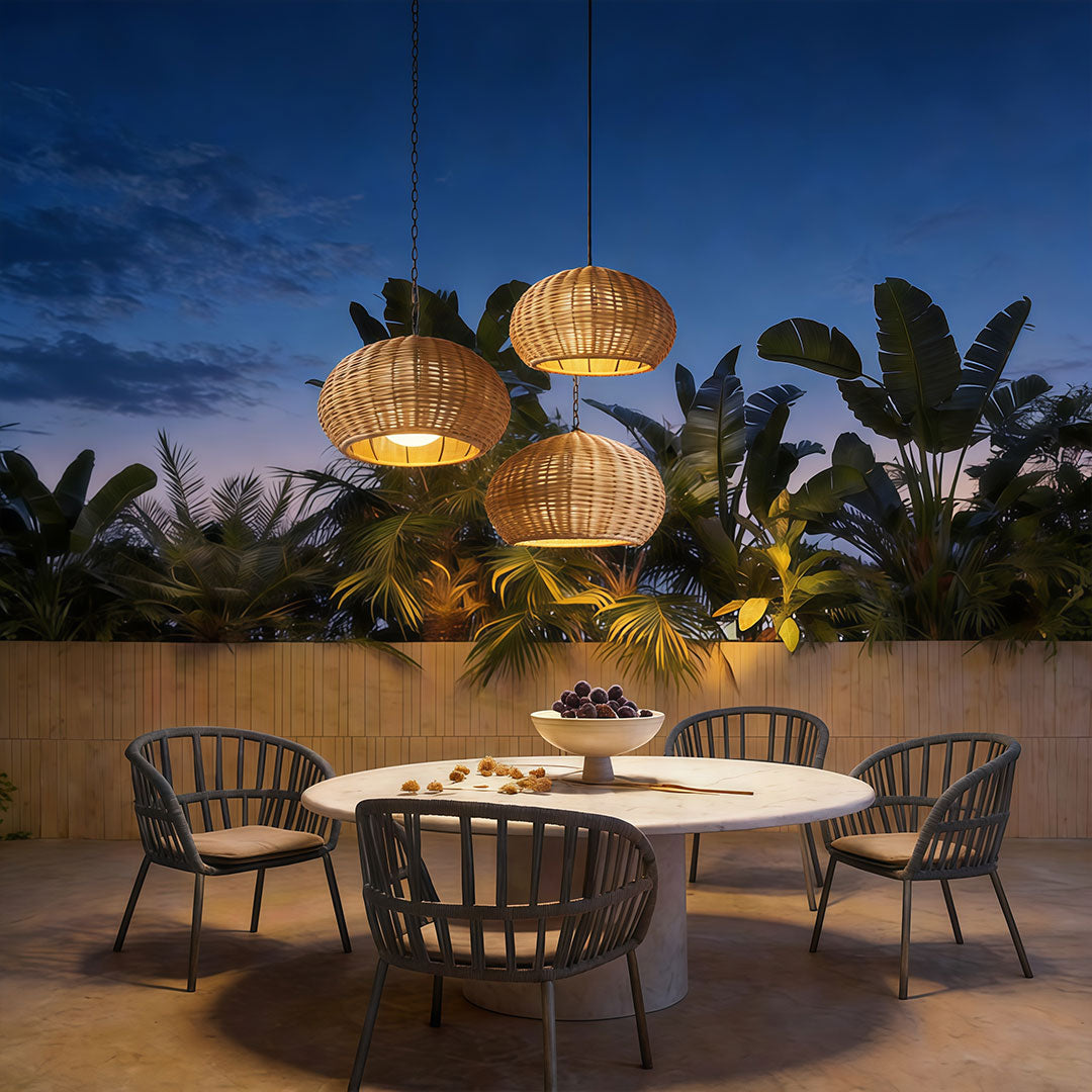 Three rattan outdoor pendant lights hanging above a modern patio dining set during the evening.