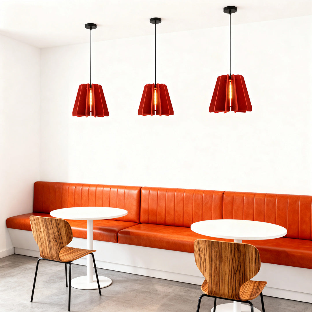 Three red felt 1 light single pendant fixtures creating a warm atmosphere above the seating area in a modern cafe.