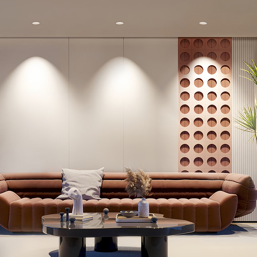 Three trimless recessed downlights creating ambient wall washing in minimalist room with leather seating