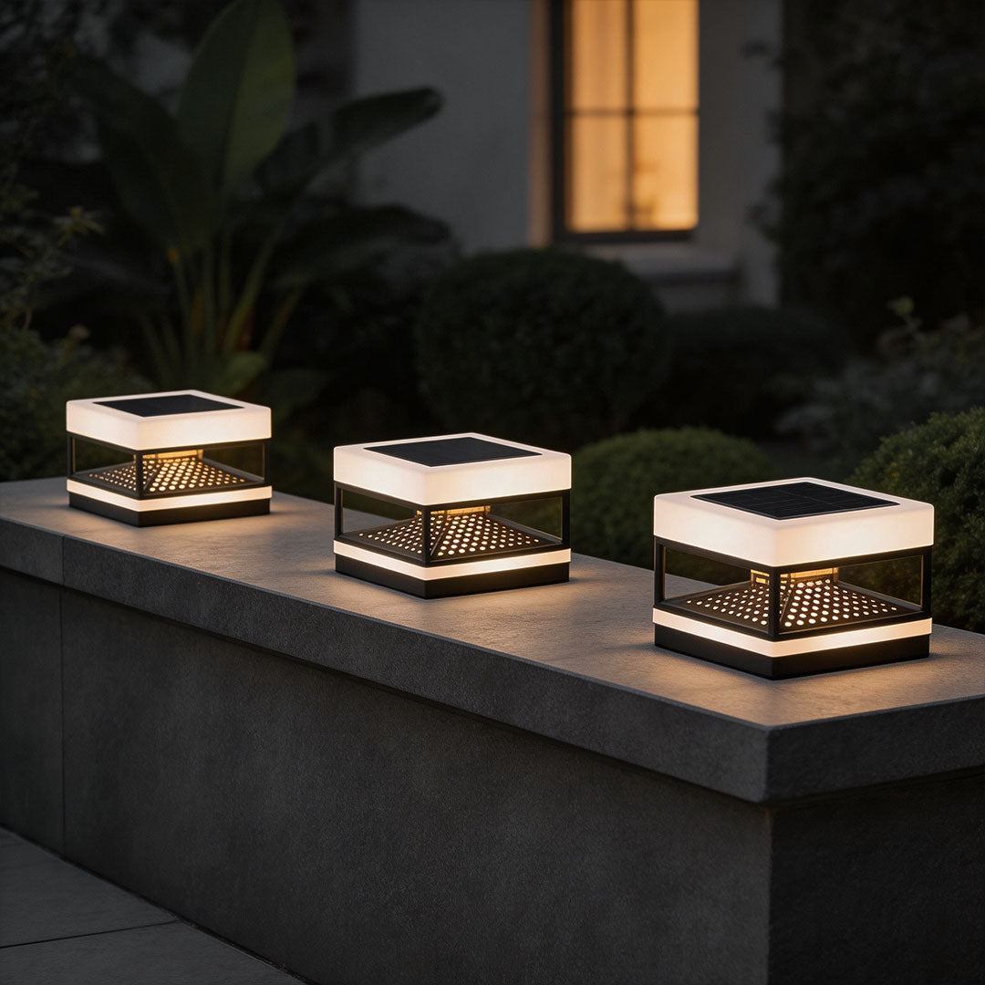 Three white pillar top lights aligned on a modern stone wall with soft ambient lighting.