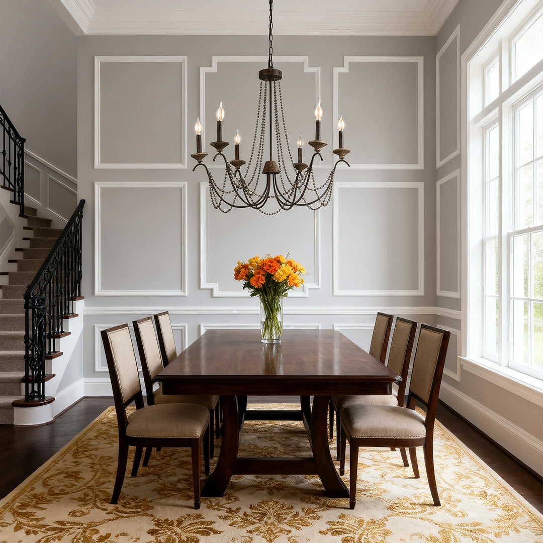 Large French style chandelier featuring multiple tiered candle-style lights, accenting a formal dining room with wainscoting and dark wood.
