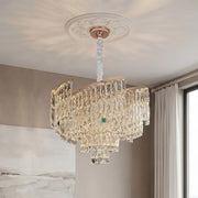 Luxurious tiered crystal pendant chandelier featuring a gold frame, clear sparkling prisms, and subtle green accents suspended from an ornate ceiling medallion.