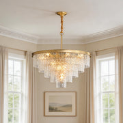 Elegant tiered modern forms chandelier featuring textured glass elements and a gold frame in a bright living space.