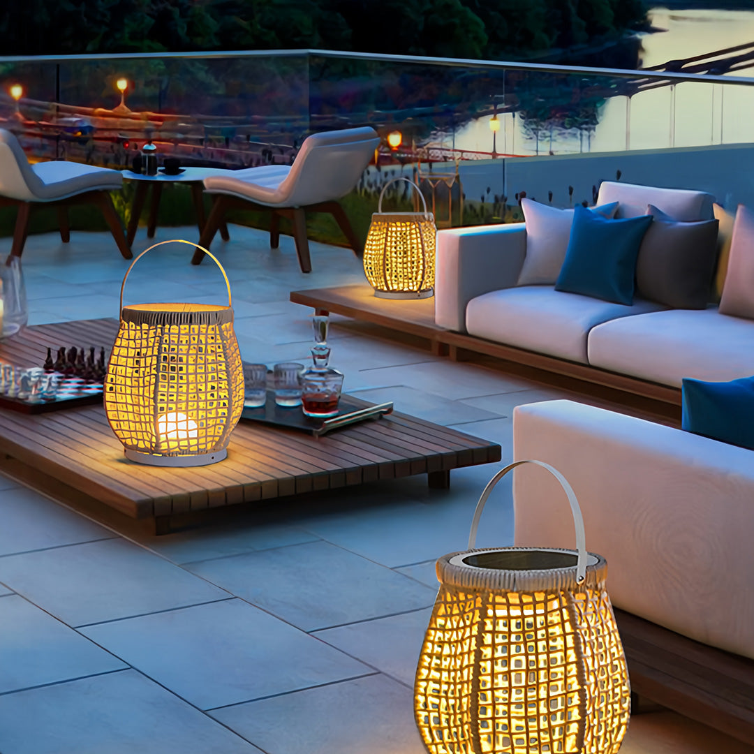 Tiered set of woven outdoor lanterns providing soft ambient light on a modern wood deck next to a pool or water feature at night.
