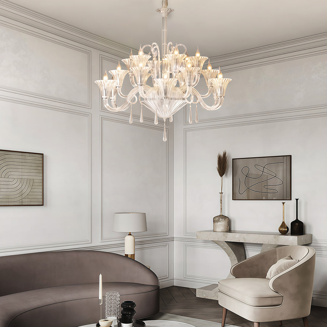 Traditional art glass chandelier illuminating bright white living room with grey sofa and framed artwork.