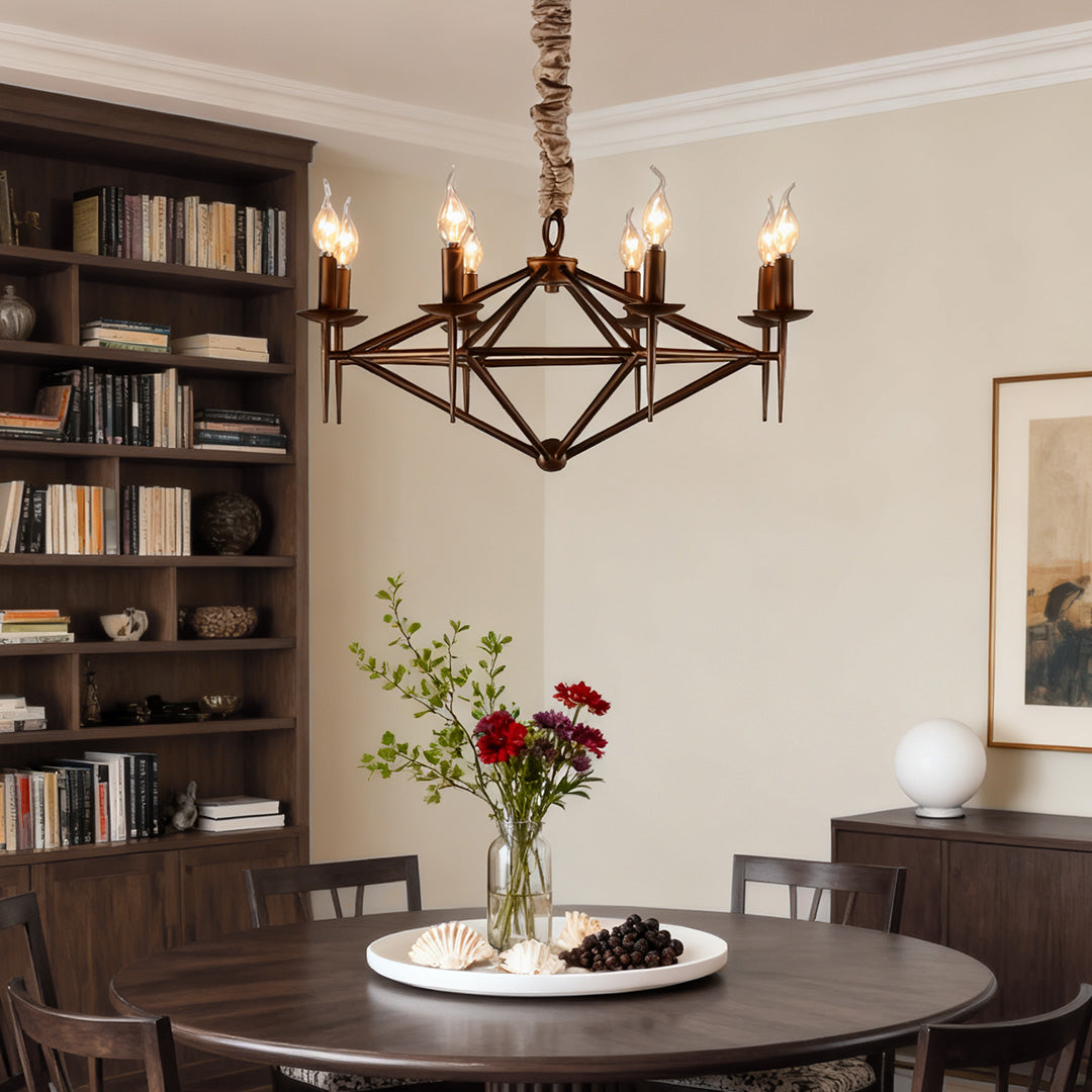 Traditional brown chandelier with faux-rope detail and exposed candle lights, centered in a room with a dark wood bookcase and round table.