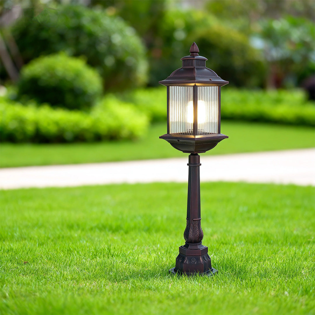 Traditional style LED post light with bronze finish illuminating manicured lawn in outdoor landscape