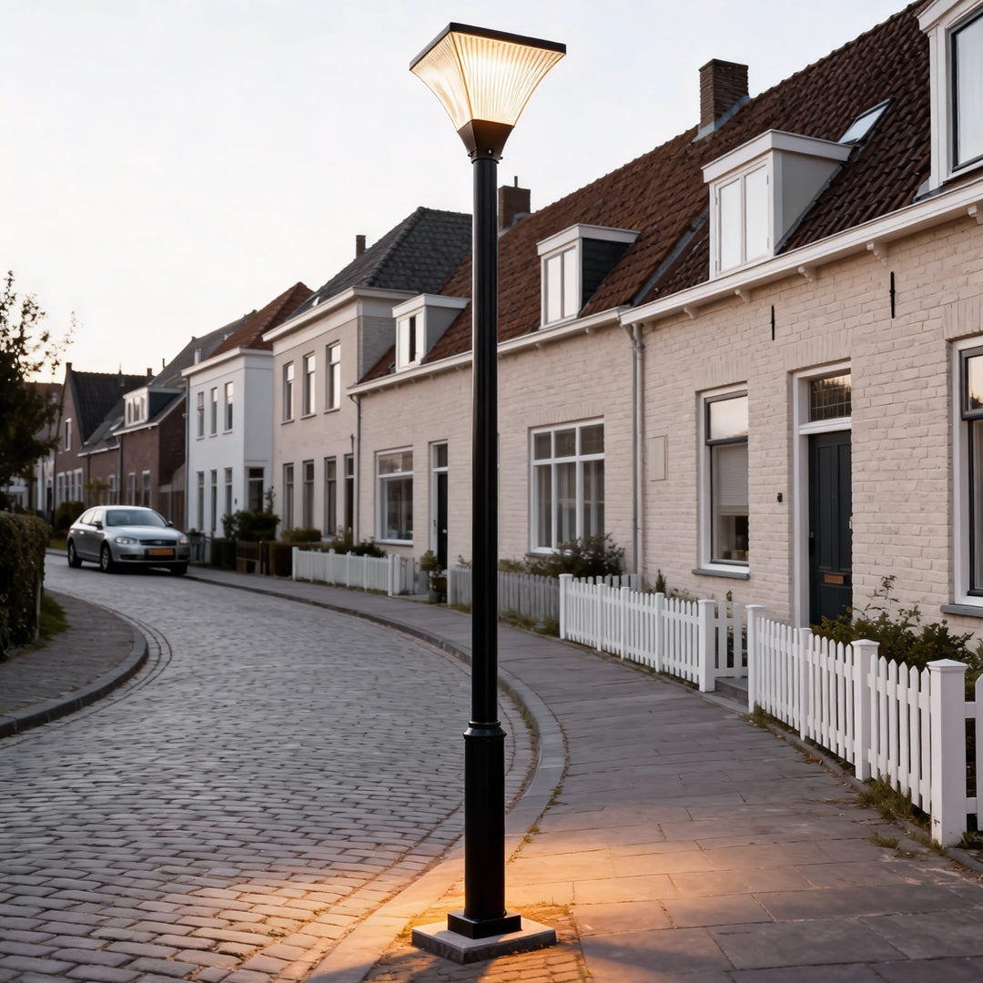 Traditional night street light casting warm light along a residential cobblestone street at dusk.