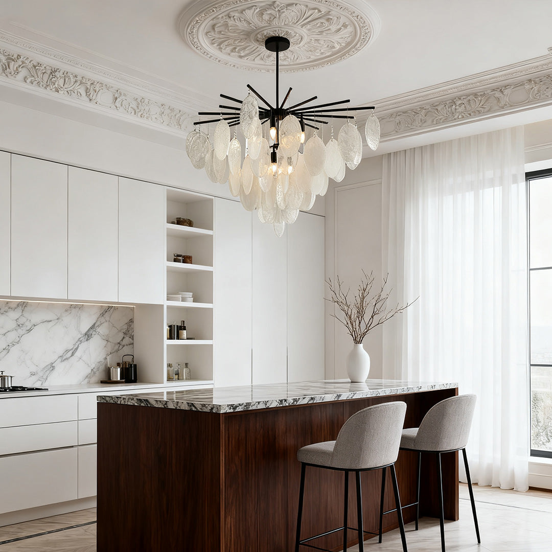 Mother of pearl chandelier illuminating a transitional kitchen island with a dark wood base and white marble countertop.