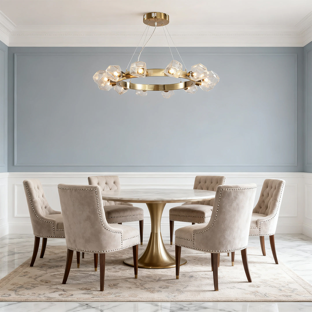 Transitional dining space showcasing a gold round chandelier with vintage bulbs, illuminating a velvet-upholstered seating arrangement.