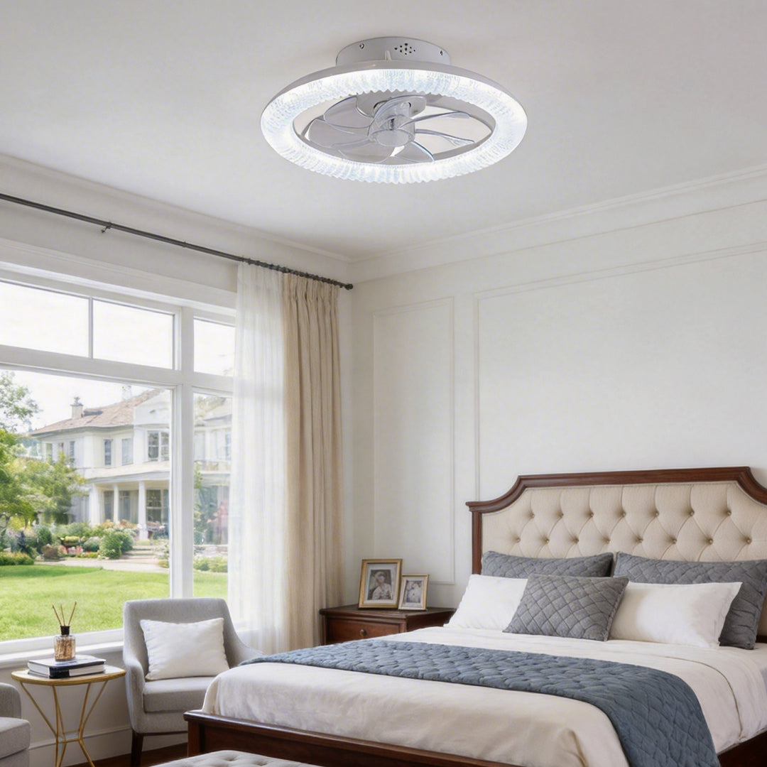 Transparent blade ceiling fan with light, installed in a modern bedroom with large windows.