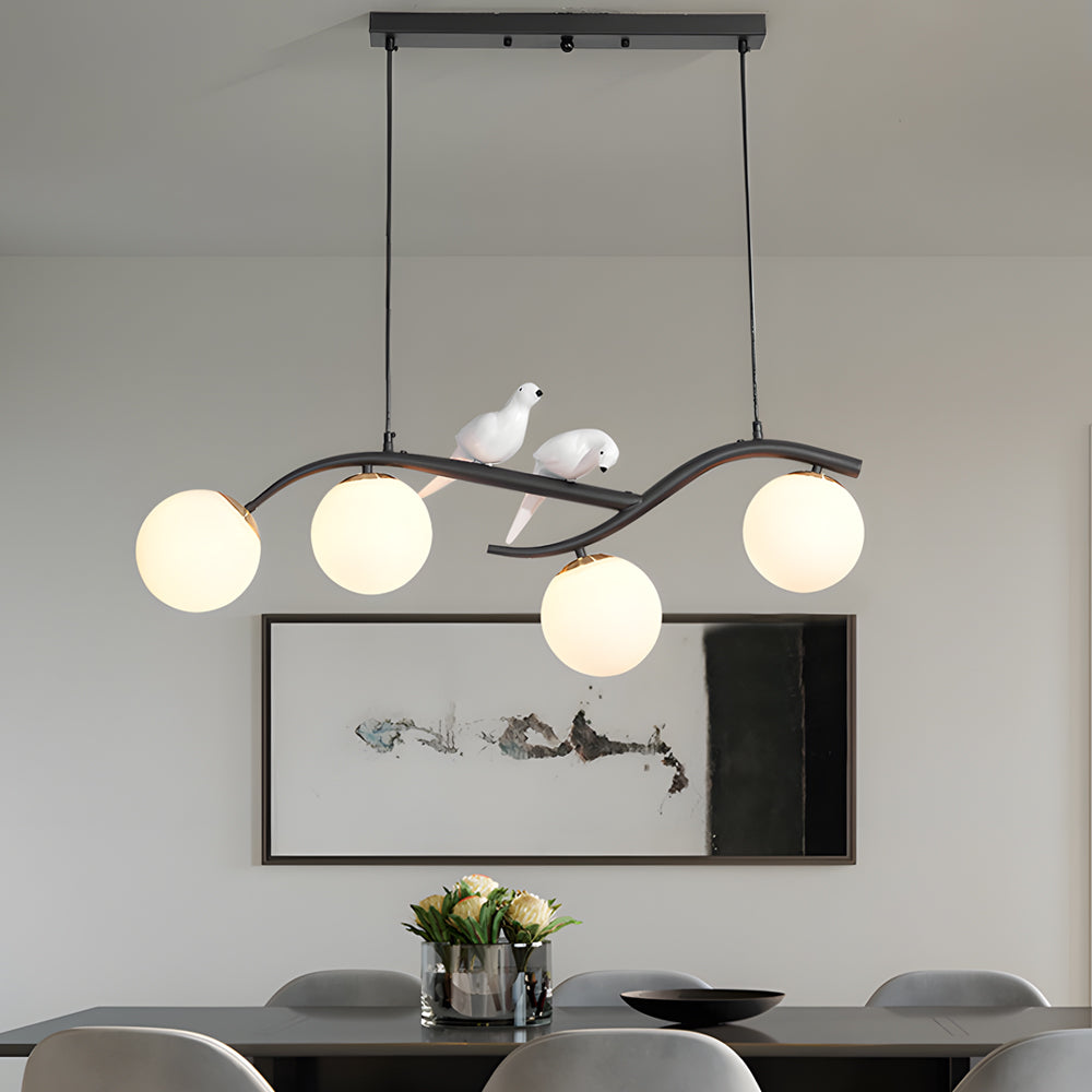 Modern tree branch pendant light with bird accents above dining table.
