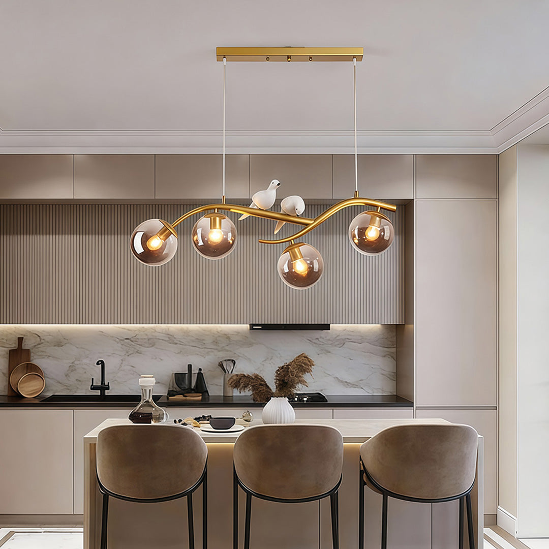 Tree branch pendant light over kitchen island with glass globe shades.