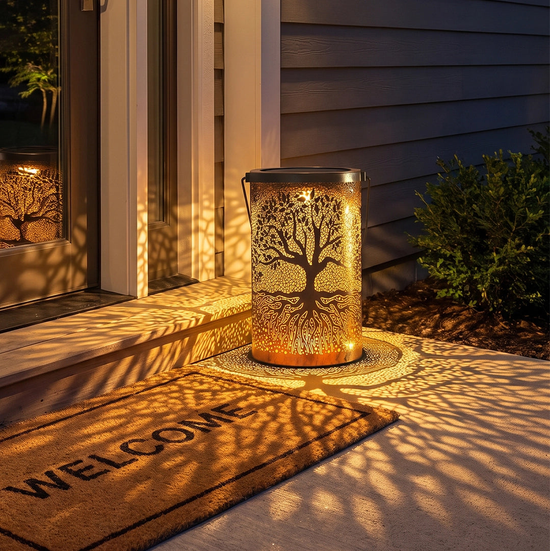 Tree of life lantern glowing beside a front door and casting intricate tree shadows across the entryway.