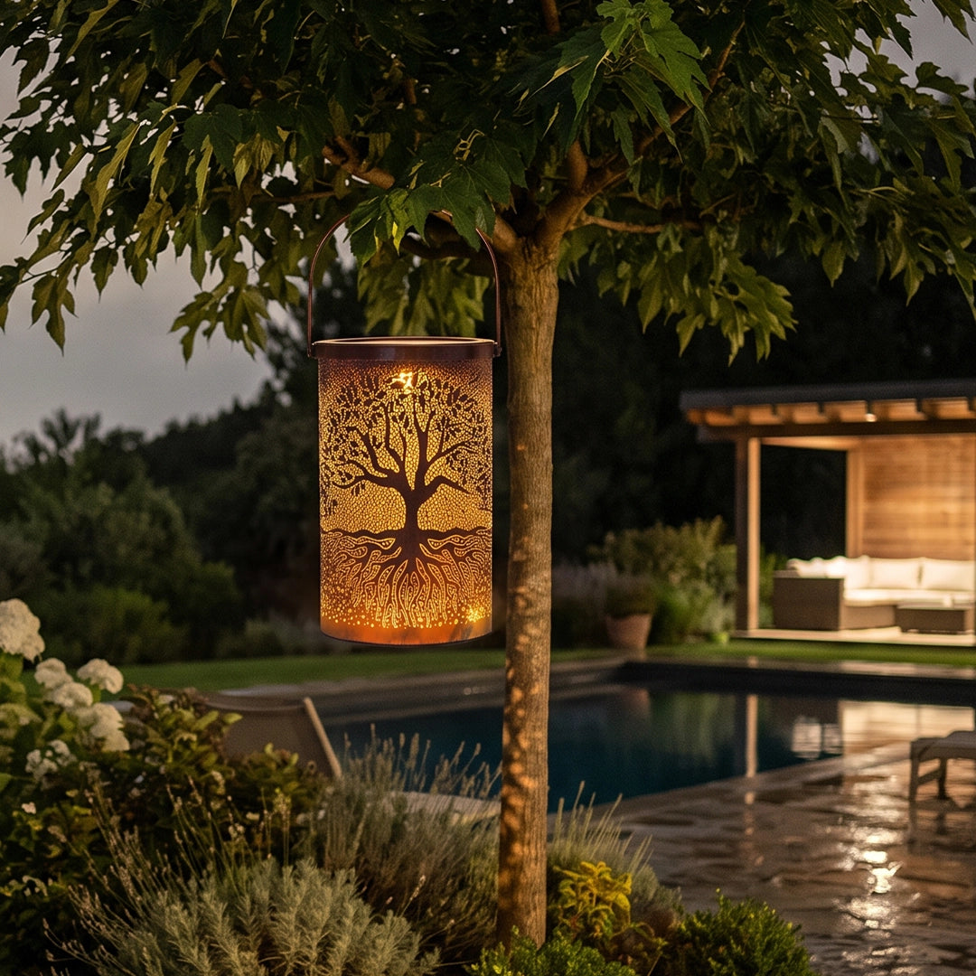 Tree of life lantern glowing beside a tree and pool, creating warm decorative light outdoors.