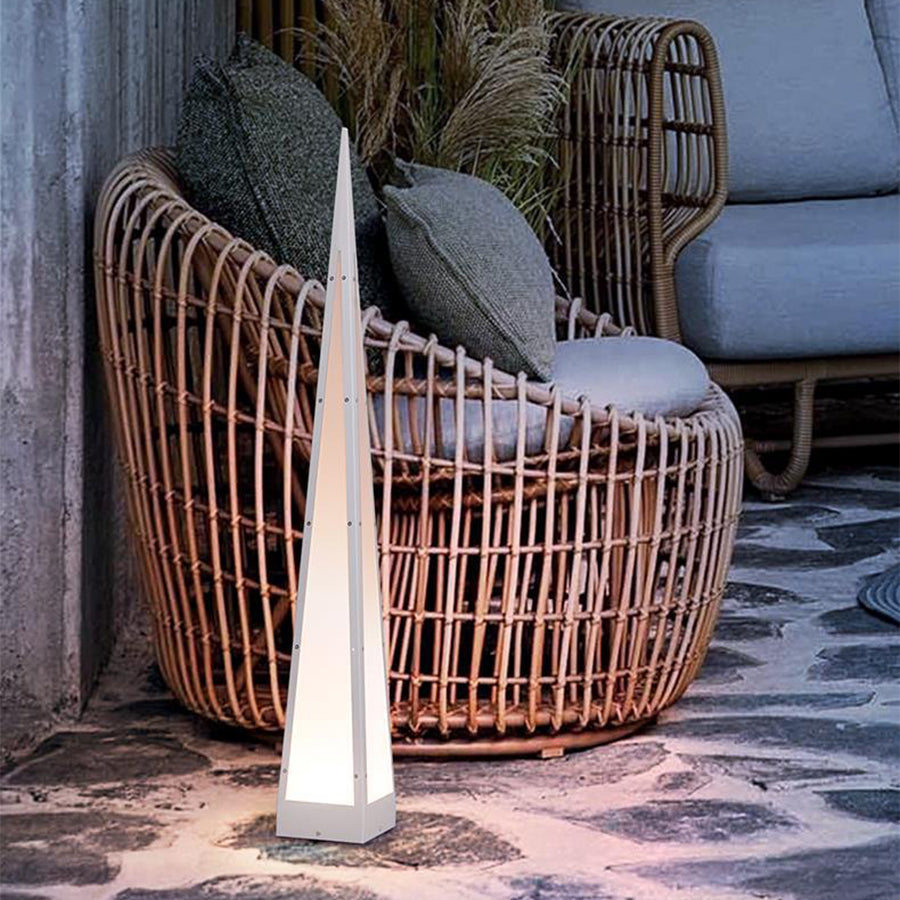 Elegant triangular lamp positioned near wicker furniture in outdoor terrace setting