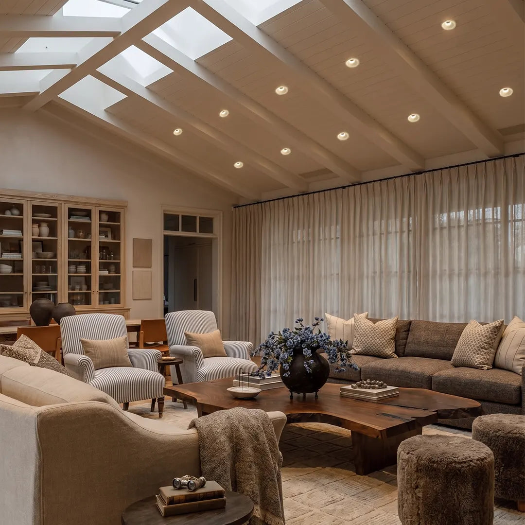 Trimless recessed downlights integrated into a bright living room ceiling, creating subtle overhead lighting above a contemporary seating area.