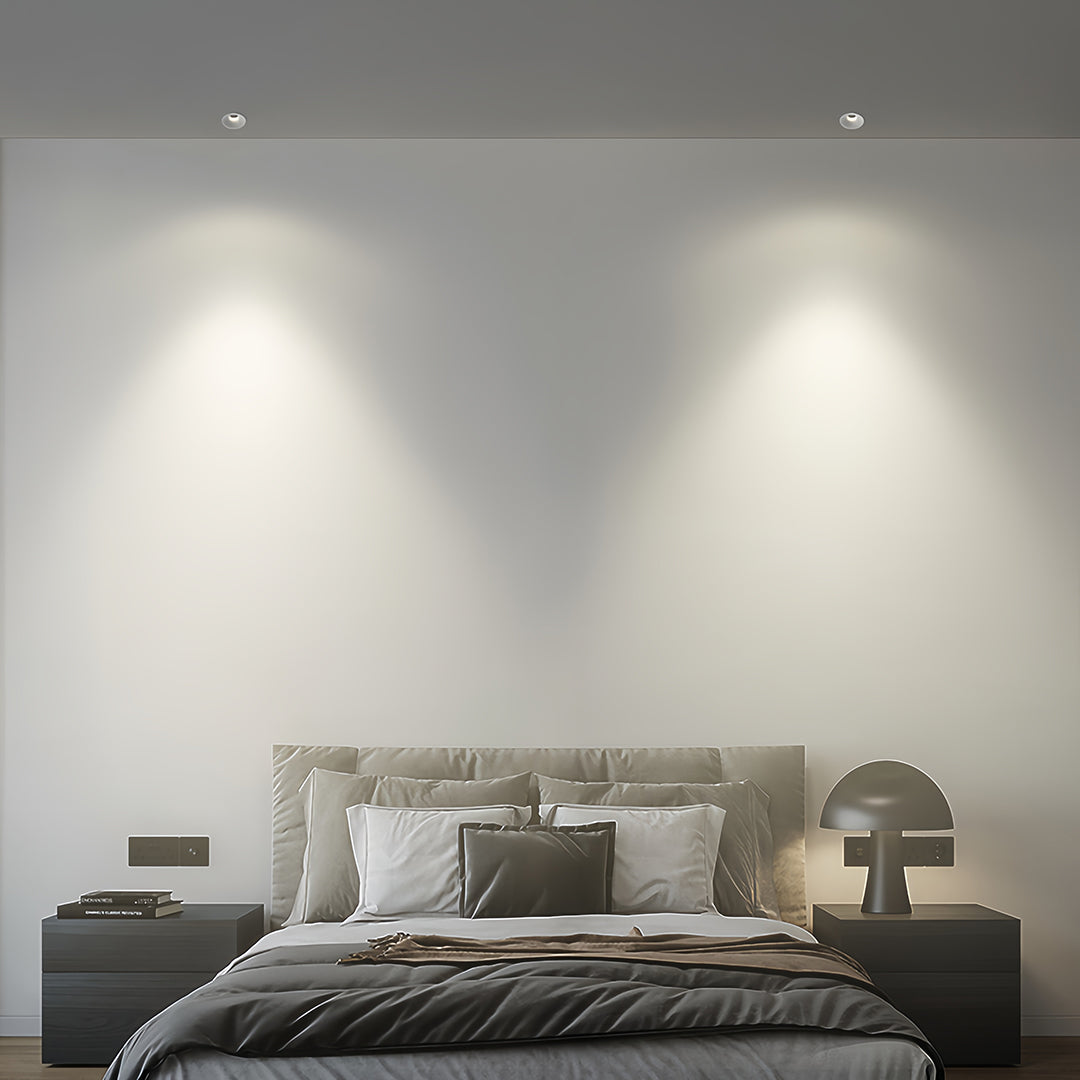 Trimless recessed downlights providing soft illumination in neutral bedroom with upholstered headboard