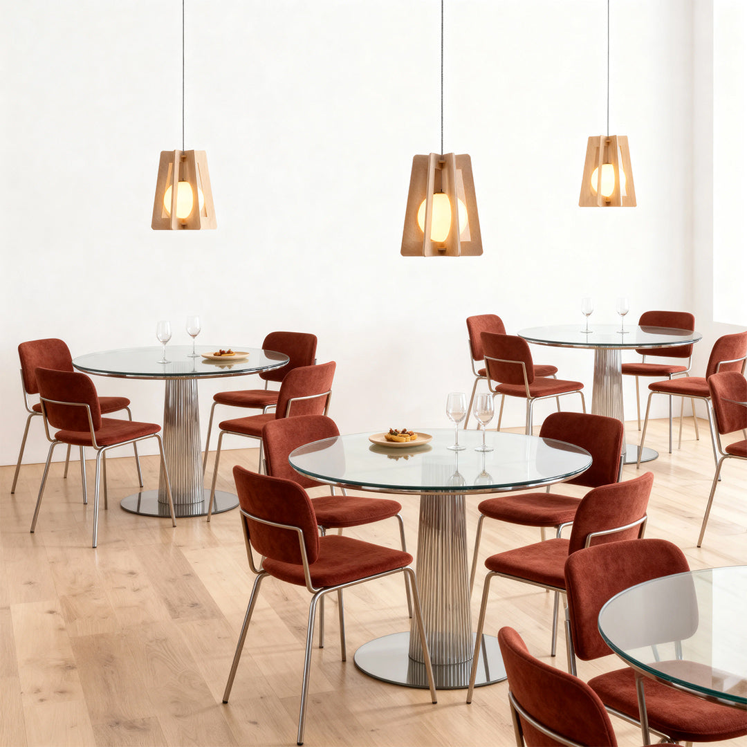 Trio of warm amber felt fun pendant lights casting a soft glow on round cafe tables and red velvet seating. 