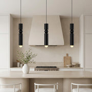 Trio of black cylinder pendant lights featuring a sphere over a luxury marble kitchen island.