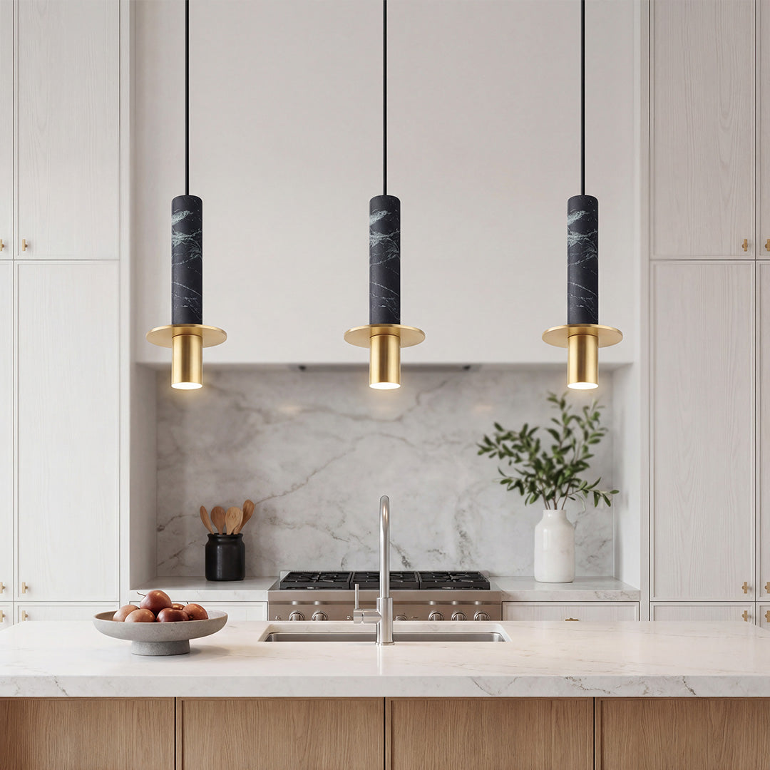 Trio of chic black marble alabaster mini pendant lights with gold hardware over a kitchen island.