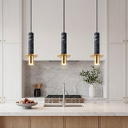 Trio of chic black marble alabaster mini pendant lights with gold hardware over a kitchen island.