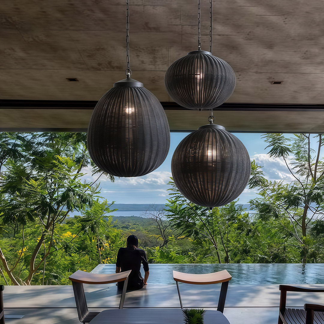 A trio of black woven pendant lights illuminating a modern dining area with a minimalist design.